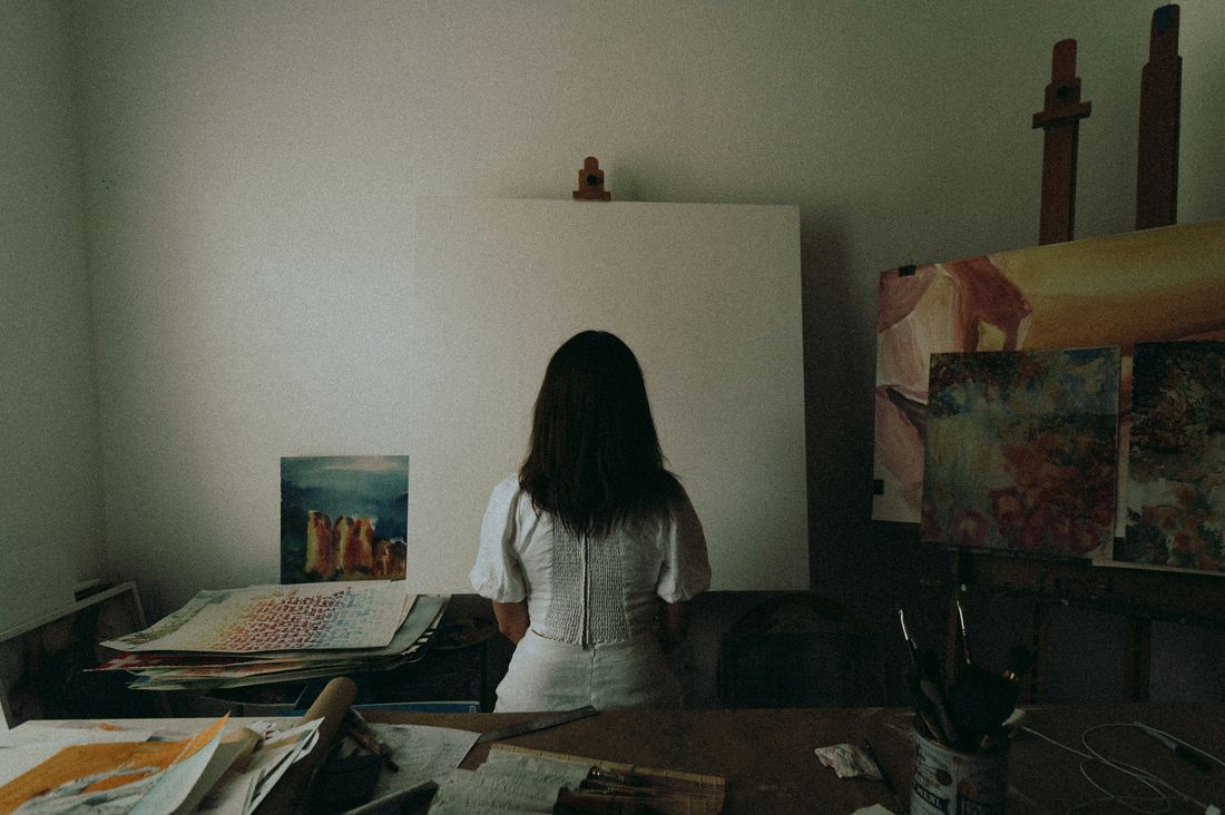 An artist standing before a blank canvas in a studio